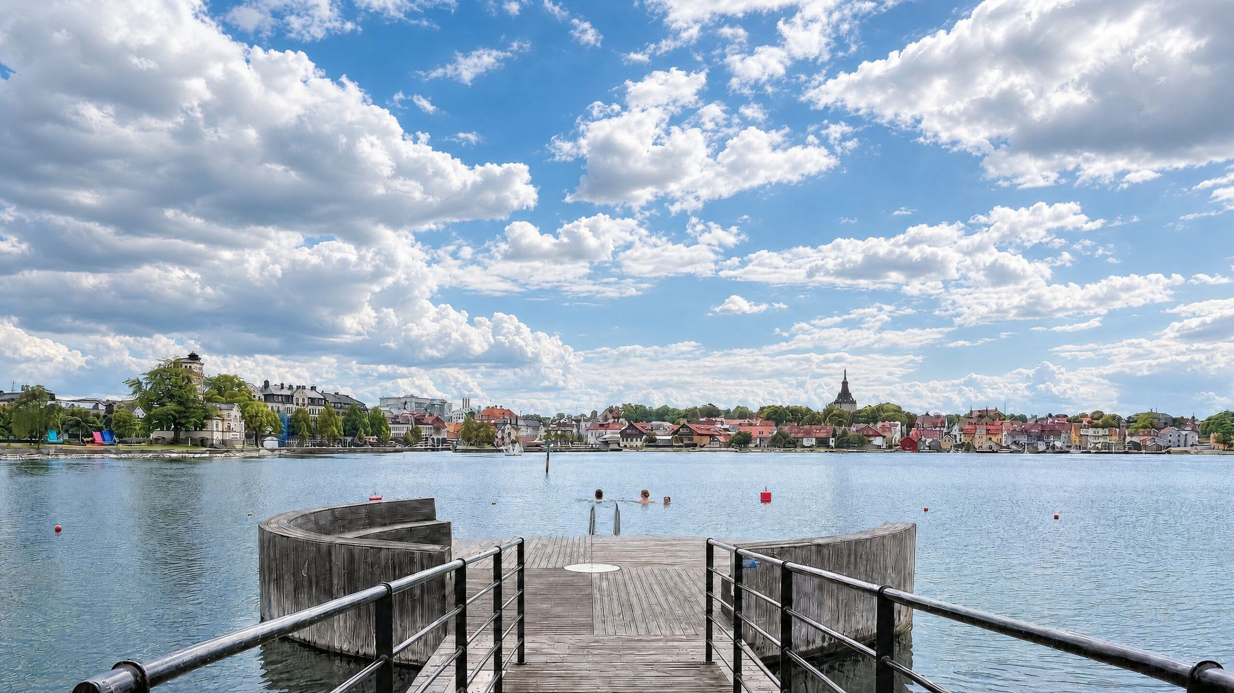 Brygga vid Västerviks vatten med stadens siluett och molnig himmel